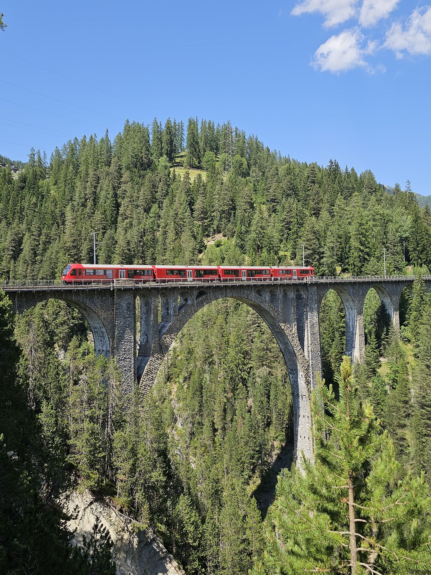 Postkartenmoment in den Schweizer Alpen 🇨🇭 
Der ikonische rote Zug der Rhätischen Bahn überquert das beeindruckende Landwasserviadukt. Ein Meisterwerk der Ingenieurskunst mitten in unberührter Natur. 
Ein Stück Schweiz, das sich anfühlt wie aus einem Märchen.
#Graubünden #Landwasserviadukt #RhätischeBahn #Switzerland #Alpenzauber #UNESCOWelterbe #Bahnromantik #Reisefieber #SchweizErleben